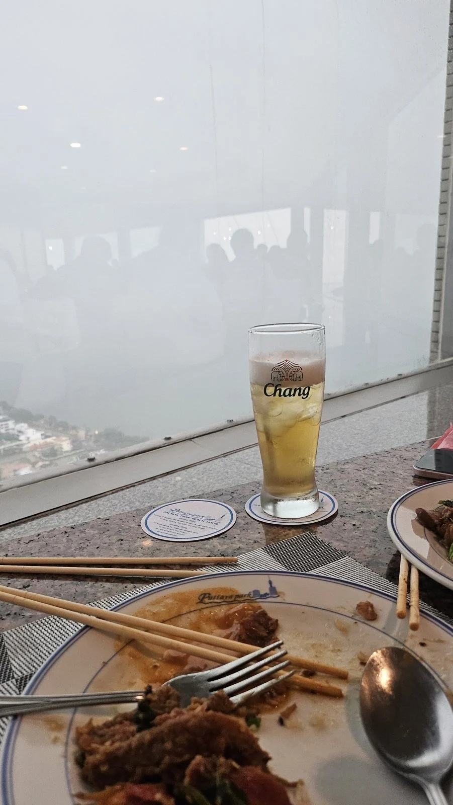 창가 테이블에 놓인 Chang 맥주잔과 식사 접시